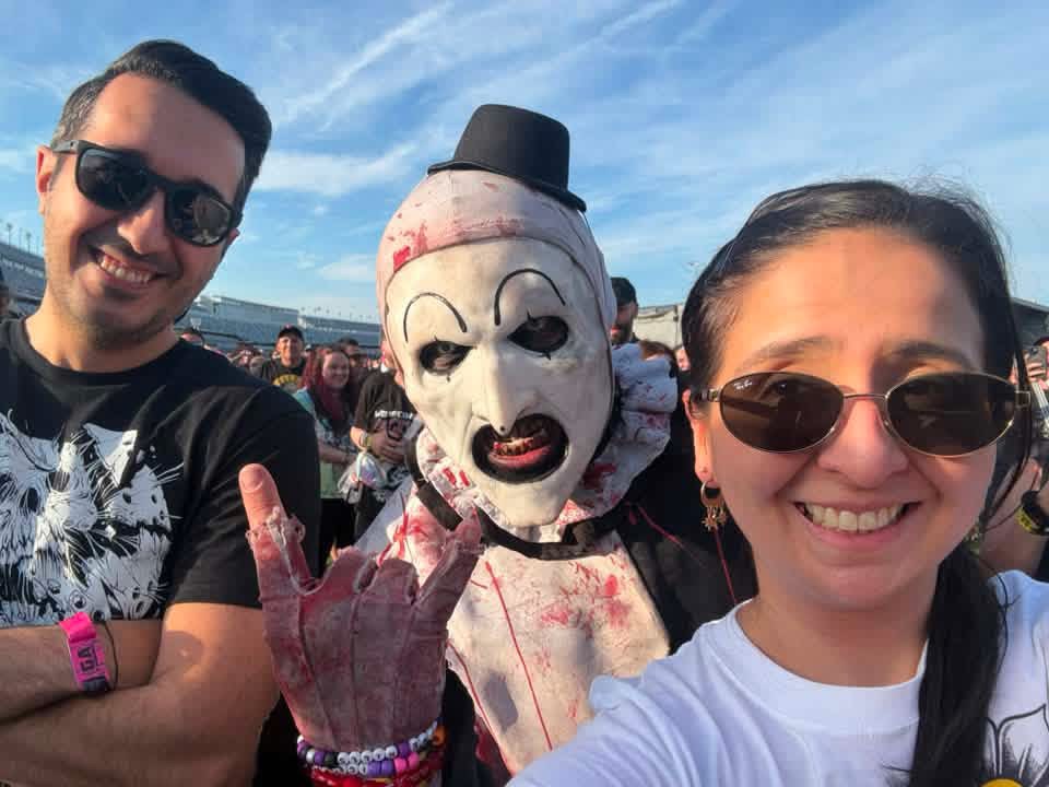 Art the Clown between two fans throwing horns in the speedway crowd