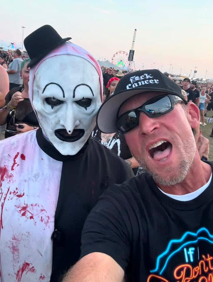 Selfie: Art the Clown with a fan in a 'F*ck Cancer' cap by the ferris wheel