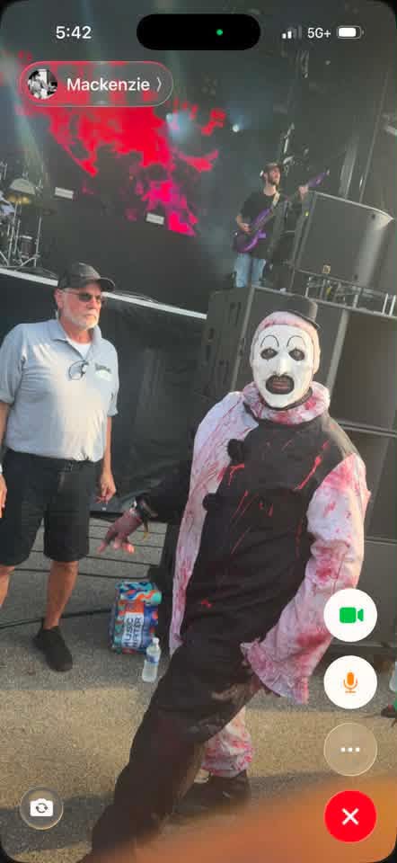 Art the Clown posing near the stage while a band plays