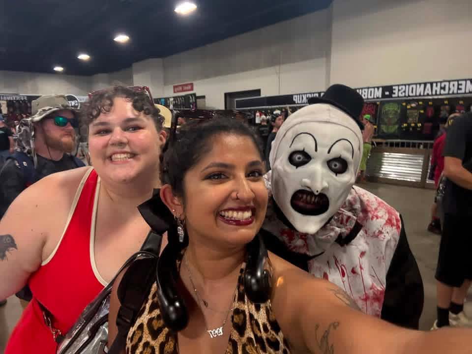 Art the Clown crashing a selfie with two friends inside the merch hall