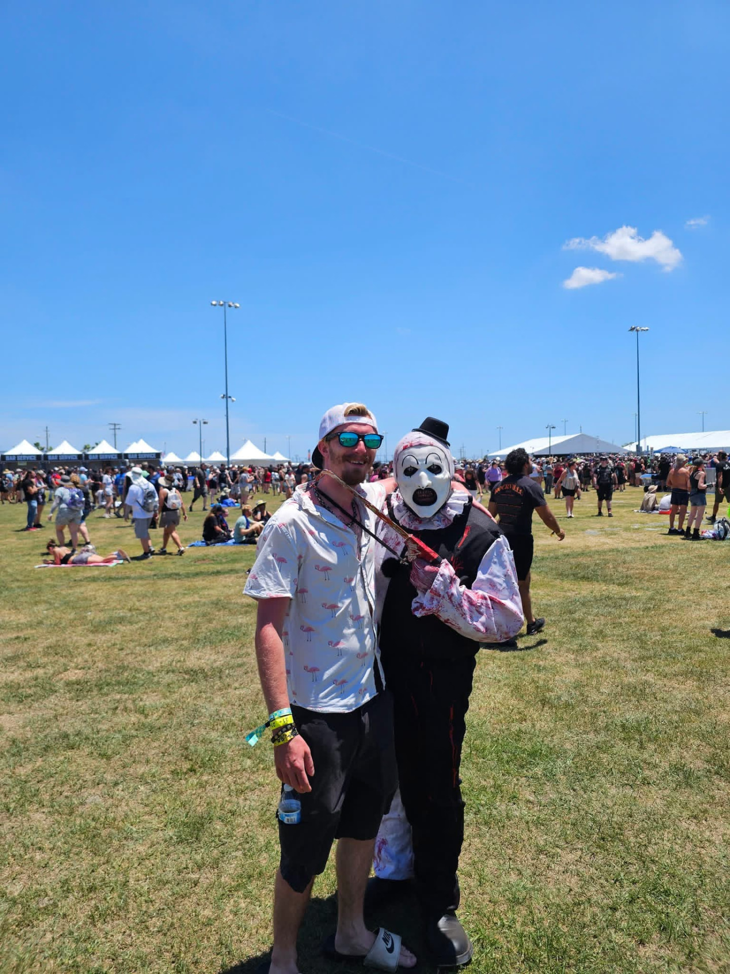 Art the Clown with a fan in a flamingo shirt on the festival field