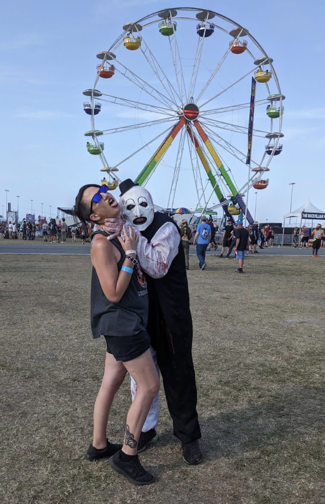 Art the Clown grabbing a fan's throat in front of the rainbow ferris wheel