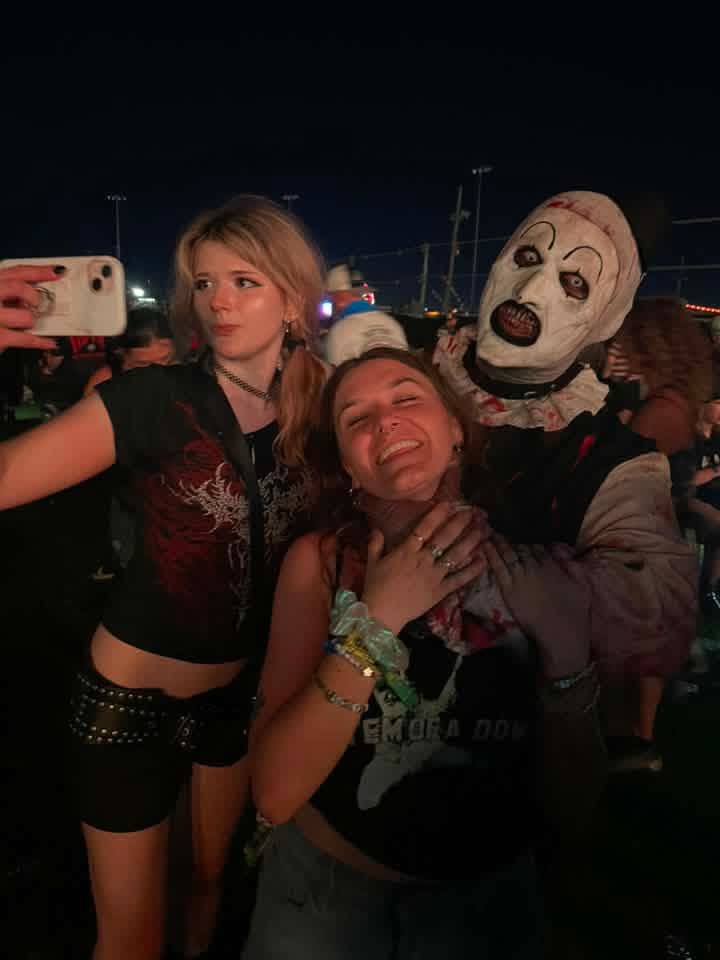 Art the Clown photobombing two friends' night selfie in the crowd