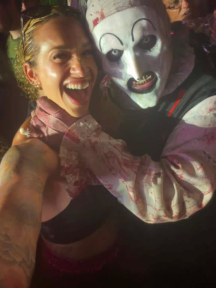 Art the Clown grabbing a laughing fan's throat in the night crowd
