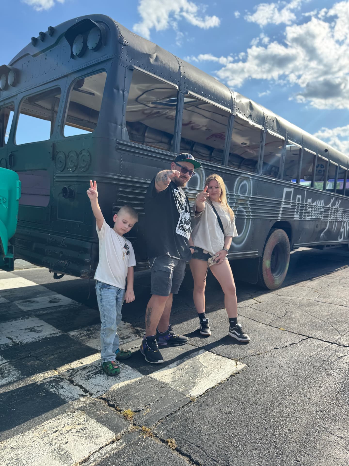 Aleksandr out of costume with his wife and son in front of a painted bus