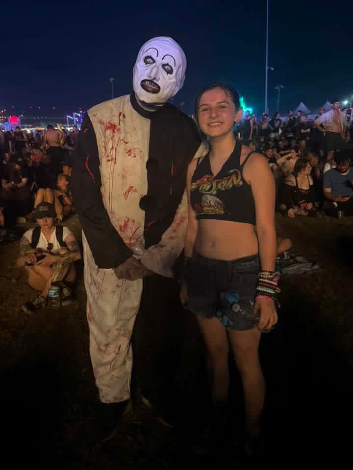 Art the Clown standing with a young fan on the field at night