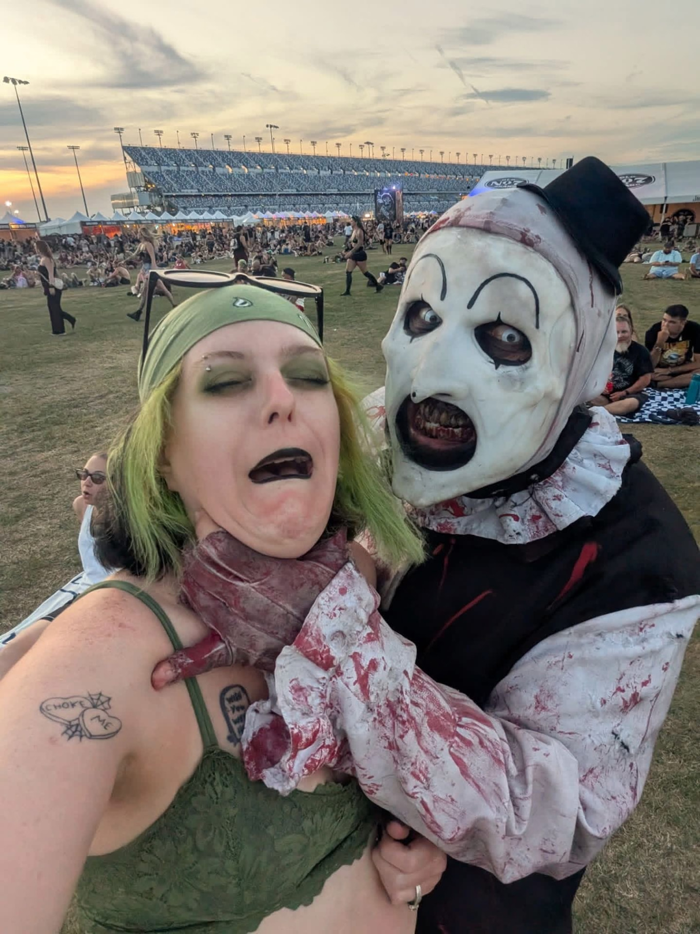 Art the Clown grabbing a green-haired fan for a selfie at Daytona Speedway