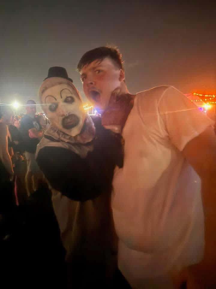 Art the Clown grabbing a fan's throat in the night crowd under stage lights