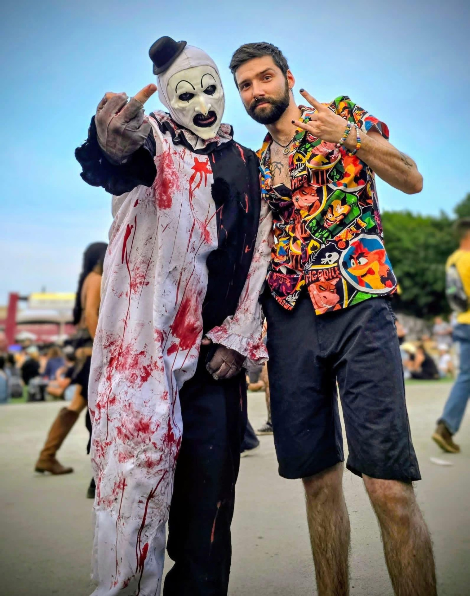 Art the Clown throwing horns with a fan in a colorful shirt at the festival