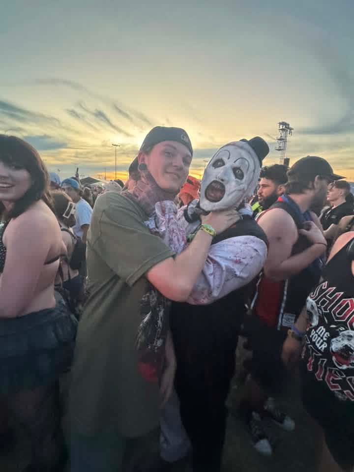A fan carrying Art the Clown in his arms in the middle of the crowd at sunset