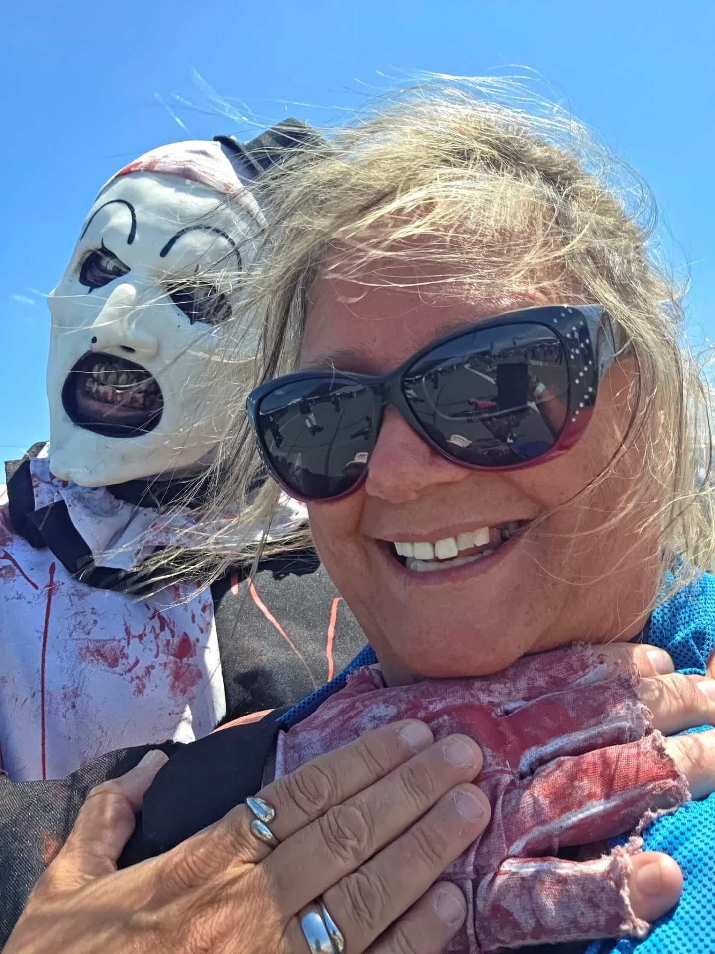 Bright blue-sky selfie: Art the Clown behind a grinning fan in sunglasses