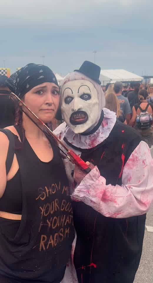 Art the Clown holding a blade to a fan's neck for a photo at the gates