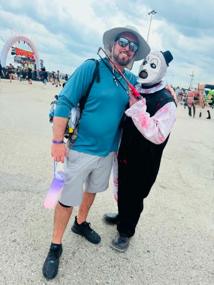 Art the Clown leaning on a fan in a bucket hat by the Rockville entrance