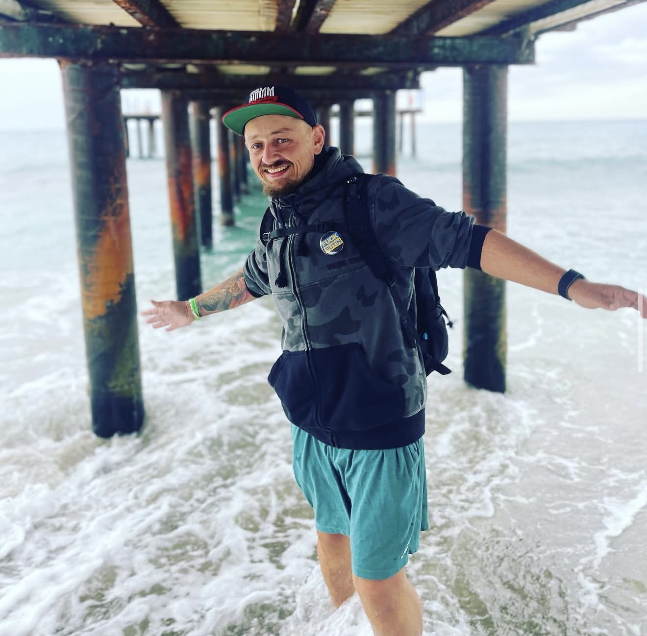 Aleksandr Nalivaiko out of costume, smiling in the ocean under a pier