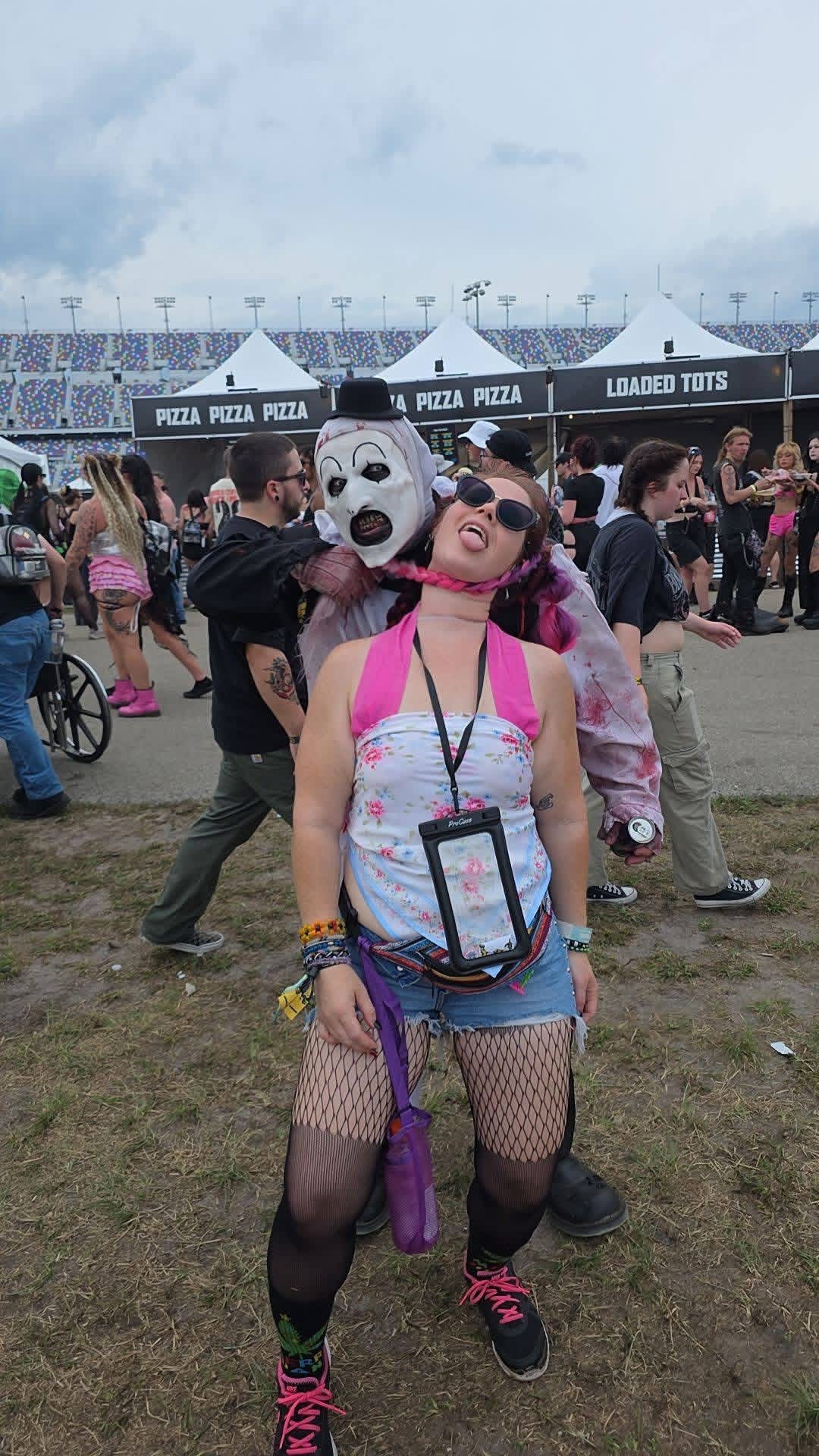 Art the Clown grabbing a fan sticking her tongue out by the food stands at Daytona