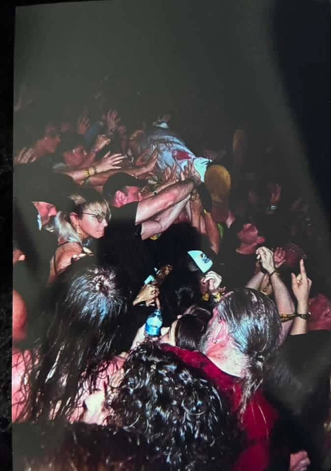 Art the Clown crowd-surfing over a sea of hands in a dark venue