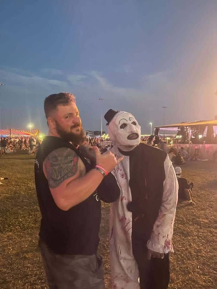 A bearded fan grabbing Art the Clown by the collar at dusk