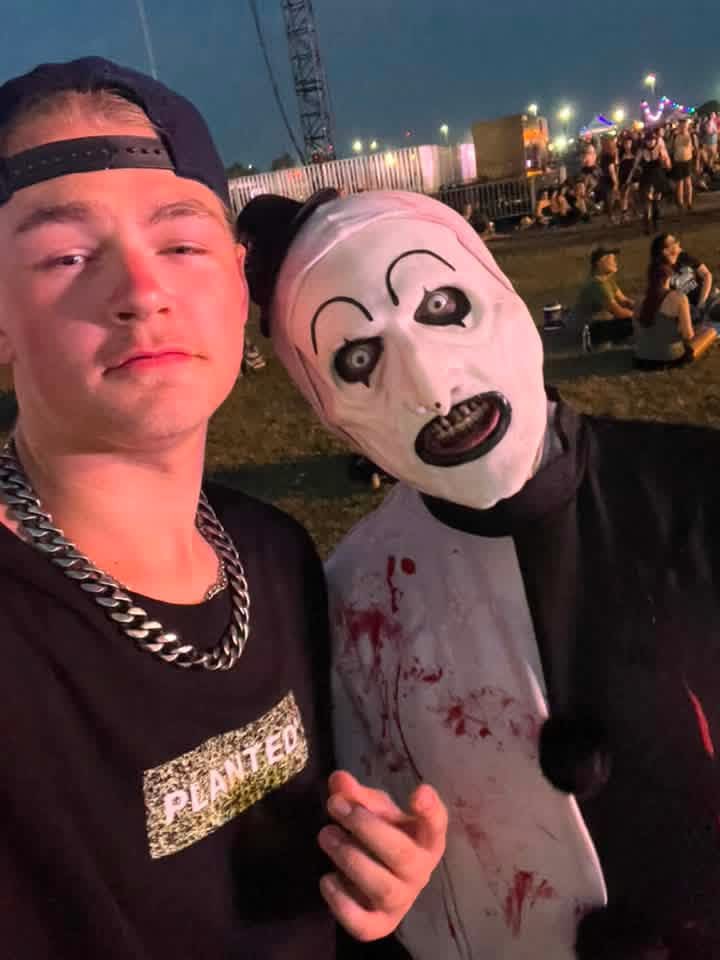 Blue-hour selfie: Art the Clown leaning into a fan in a backwards cap