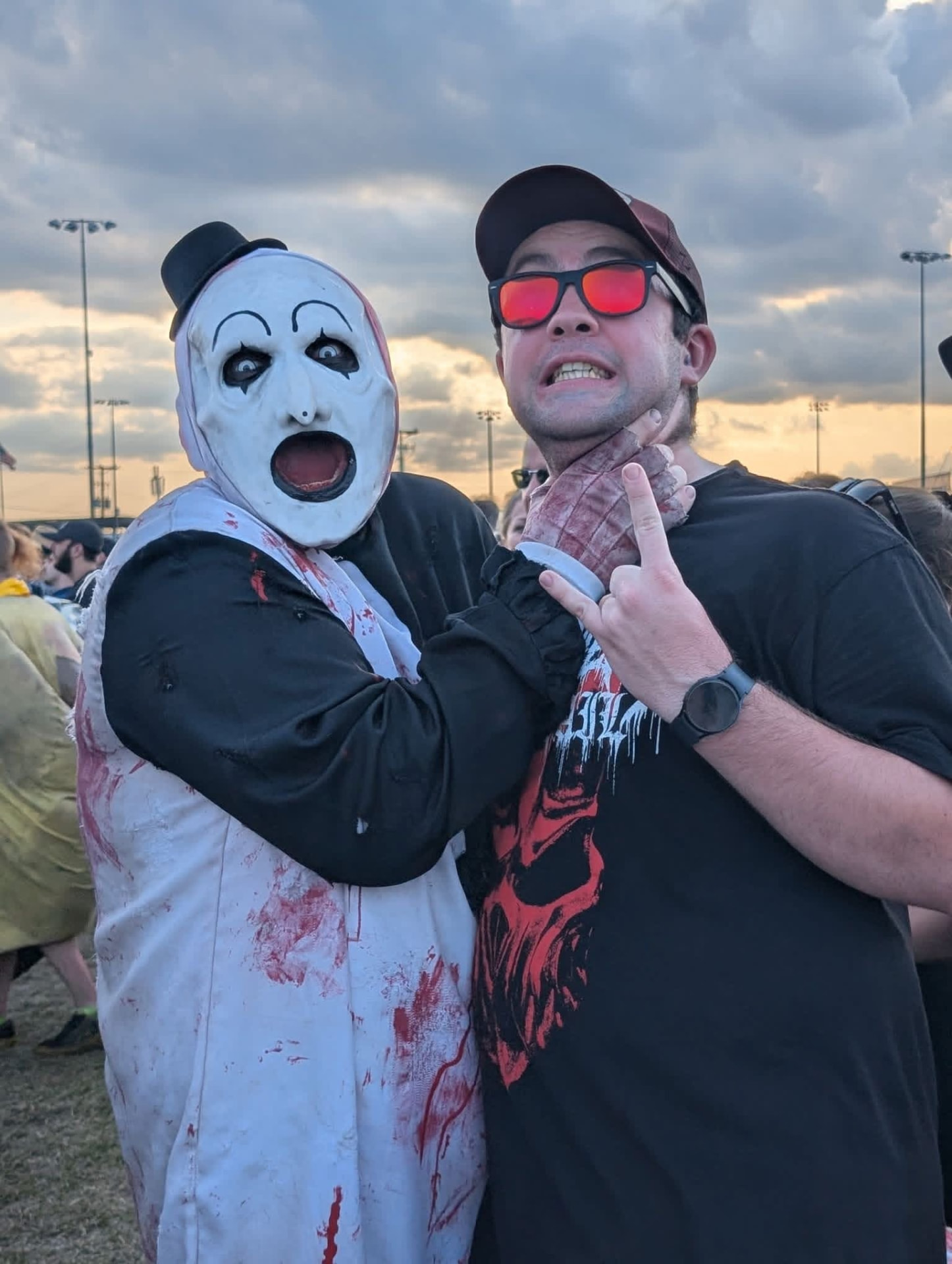 Art the Clown with his hand on a fan's throat under a stormy sunset sky