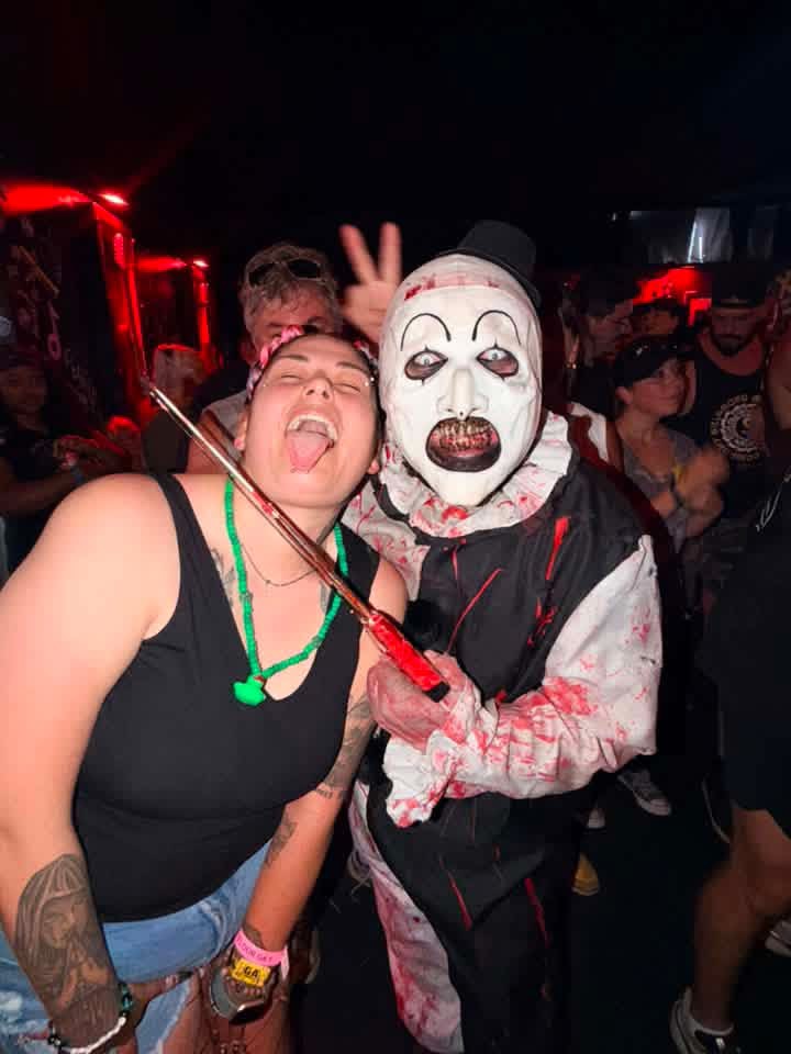 Art the Clown throwing up a peace sign with a laughing fan under red lights