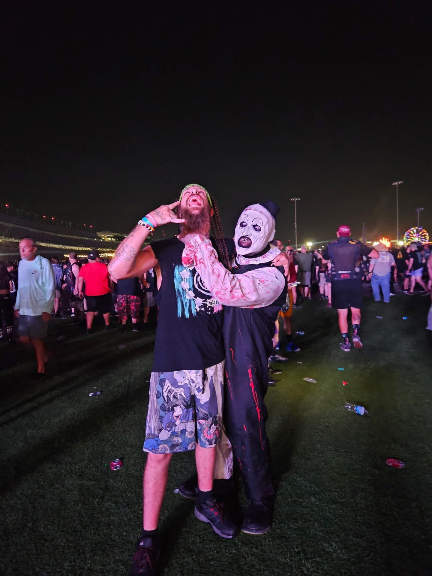 Art the Clown hugging a screaming bearded fan on the night field